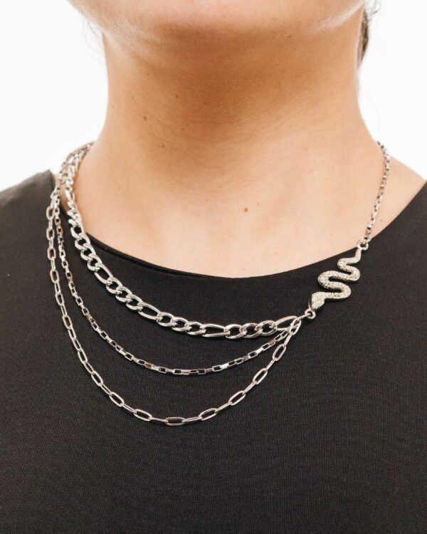 Accesorio con tres tipos de cadenas que se unen a dije de serpiente. Cadenas de acero quirúrgico con serpiente de niquel